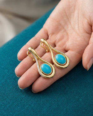 Firouzeh Turquoise Drop Earrings on hand against teal surface