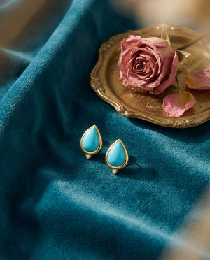 Firouzeh Turquoise Stud Earrings styled on teal surface with Persian tea